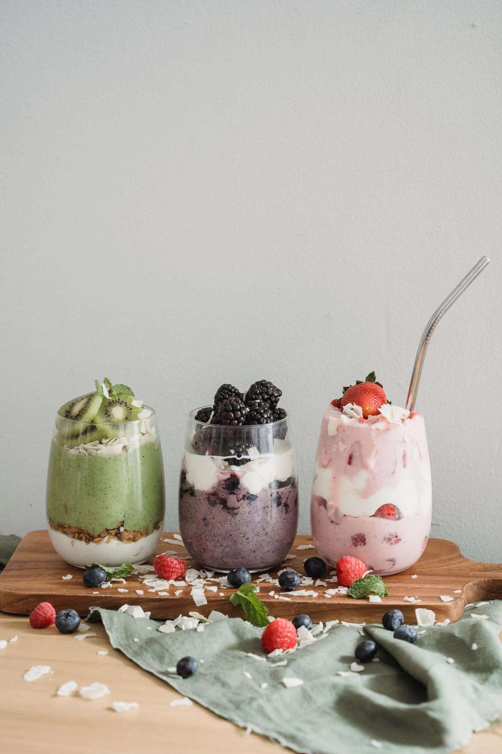 Three colorful fruit yogurt drinks with fresh berries